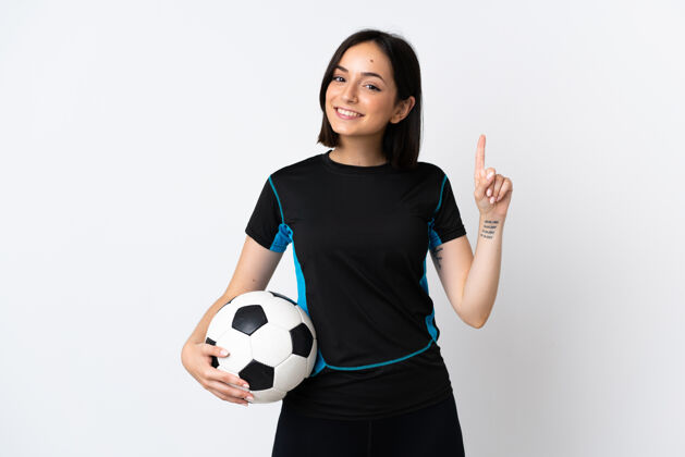 年轻人一个年轻的足球运动员 一个孤独的女人站在白色的墙上 指着一个好主意微笑自信展示