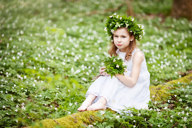可爱穿着白裙子的漂亮小女孩在春天散步伍德肖像画美丽的小女孩头上戴着春花的花环乐趣举行阳光