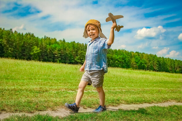 活跃飞机旁的一个男婴在空中玩弄大自然公园男孩度假飞行员快乐飞机年轻