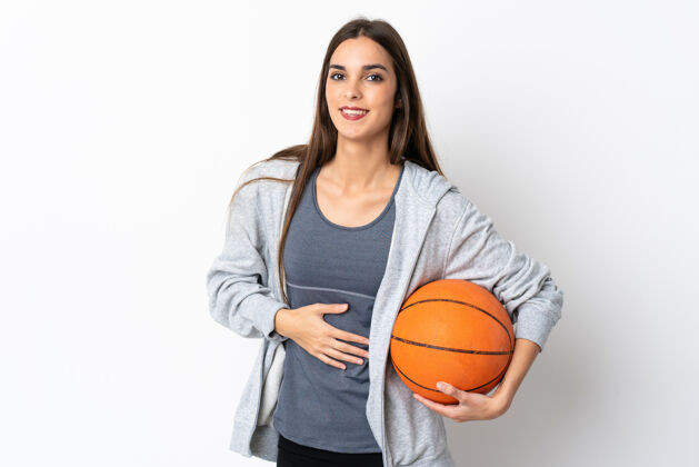 运动装在白色背景上打篮球的年轻女子面带微笑大笑运动员篮球