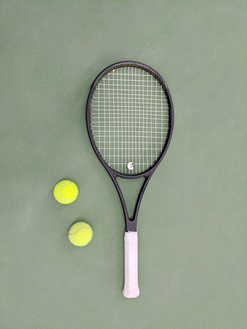 球场网球拍和两个球在绿泥网球场上的俯视图设备背景比赛