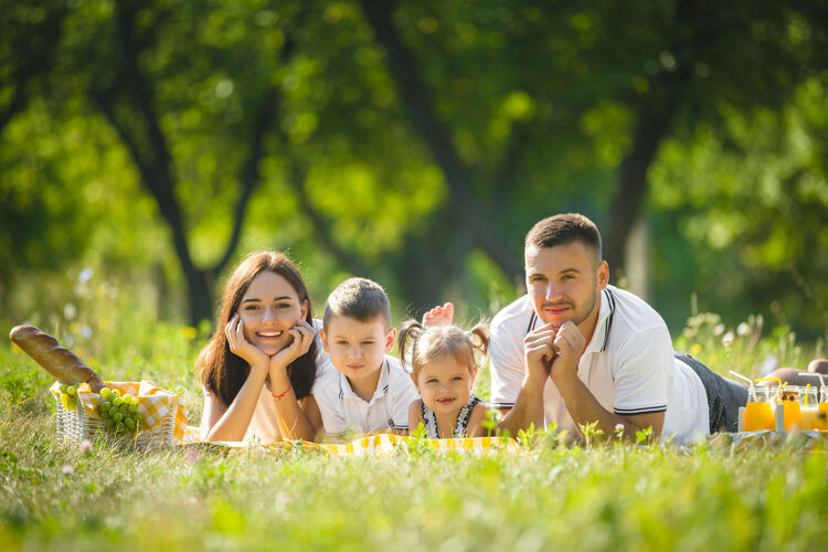 孩子快乐的家庭野餐父母在户外和孩子们一起吃晚饭情绪公园休闲