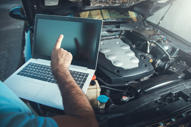 服务专业汽车修理工在汽车维修服务中使用笔记本电脑工作发动机诊断