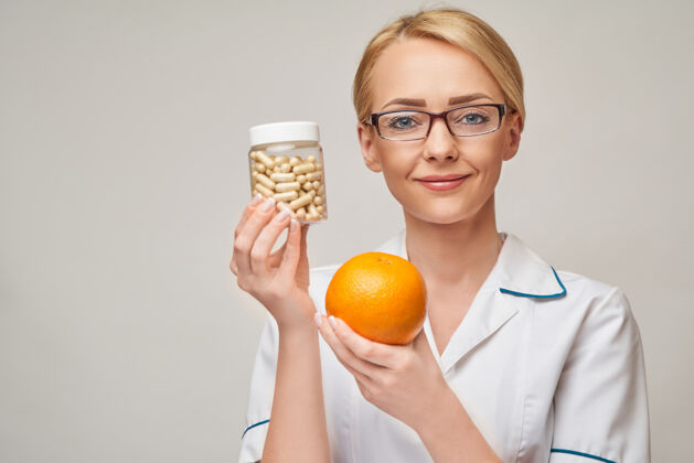 水果营养学家医生健康的生活方式概念-持有橘子水果和营养维生素胶囊或药丸橙色水果女性健康