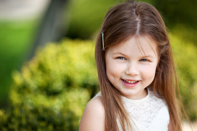 田野美丽微笑的小女孩穿着奶油色的裙子 映衬着夏日公园的绿色美丽人青少年