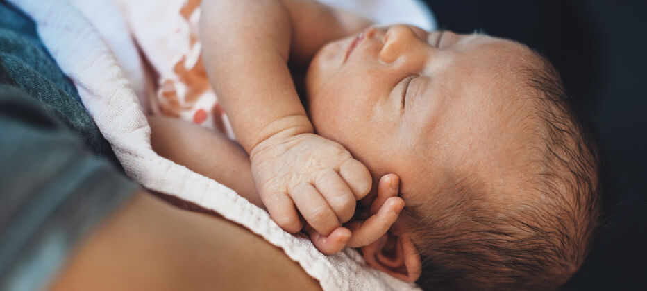 卧室一张白人新生儿的特写照片 她妈妈抱着她睡觉孩子爱手指