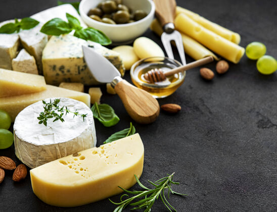 Gorgonzola各种各样的奶酪 葡萄 蜂蜜和零食放在一张黑色的水泥桌子上小吃熟食乳制品