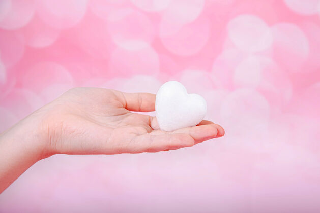 手一个小的白色的心在手上粉红色的背景与博贺问候语情人节贺卡粉彩闪光礼物