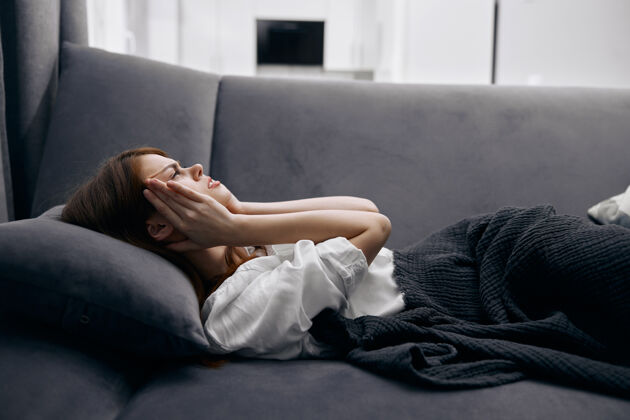成人客厅里的女人躺在沙发上手放在脸上感觉不舒服房间房子药品