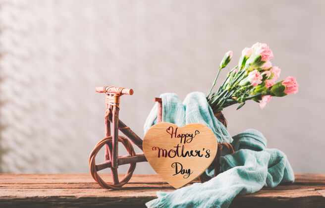 桶木桌上放着香甜的康乃馨花 木桌上放着自行车 木心上写着母亲节快乐的信息装饰自然甜蜜