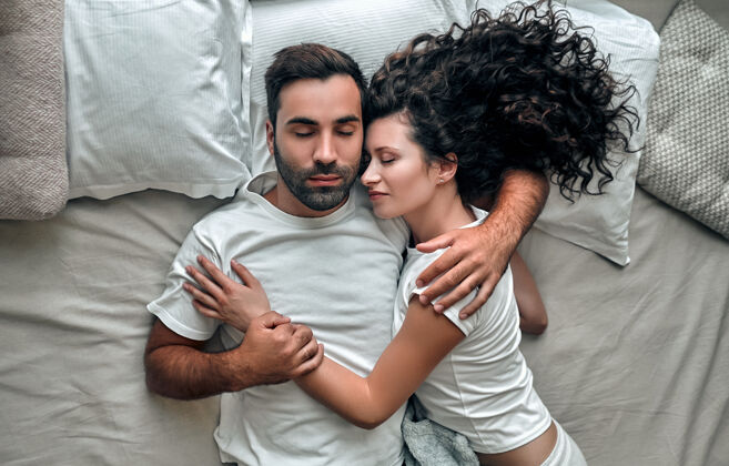 卧室俯瞰美丽的年轻夫妇拥抱而睡在一起 在家里的床上睡衣休闲爱情