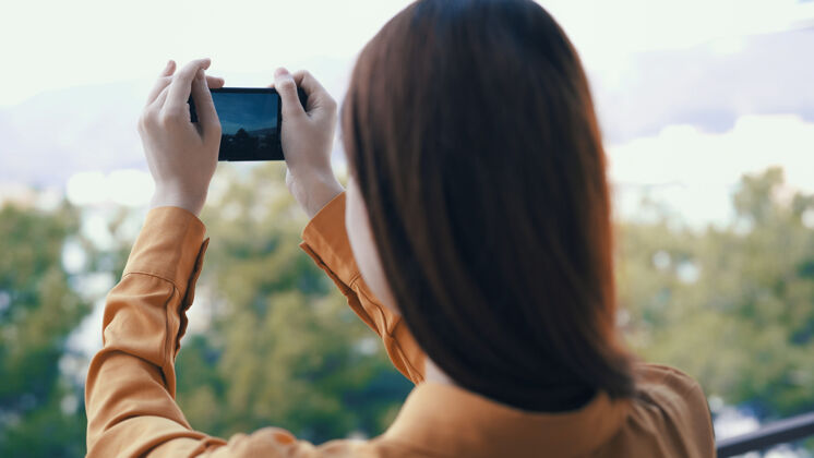 露营在户外拿着手机的女人用相机拍照小径电话绿色