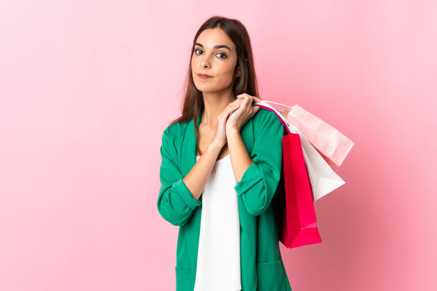 电子商务一位年轻的白人妇女 手拿购物袋 被隔离在粉色背景下女孩市场购物者
