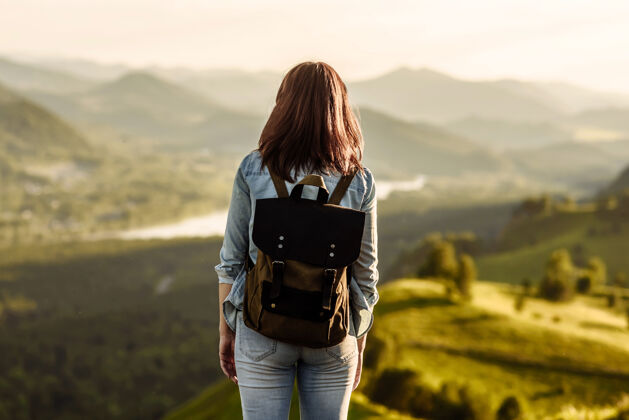 游客一个背着背包的年轻女游客站在岩石上 向山谷里望去人户外站
