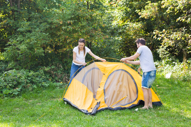 野餐一对幸福的年轻夫妇正在准备野营乡村团队合作冒险