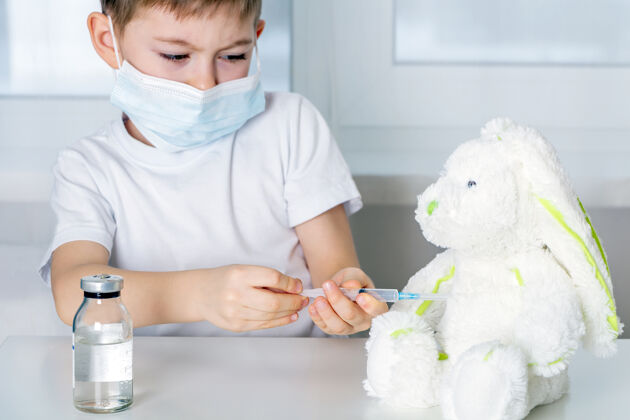 病人小男孩戴着医用防护面具玩耍 给毛绒玩具打预防针冠状病毒发展保健