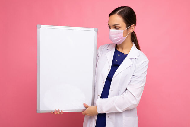 女性一名女医生 身穿白大褂 戴着口罩 手里拿着空白板 空白板上有文字隔离的复印空间背景.冠状病毒概念黑发青年防护