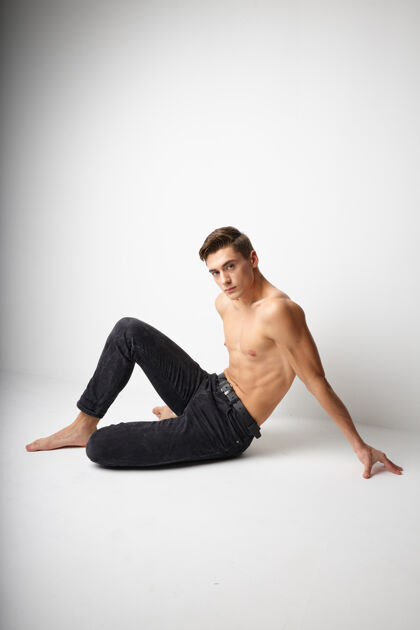 时尚男人穿着黑色裤子坐在地板上裸体摆出优雅的姿势肌肉休闲肌肉
