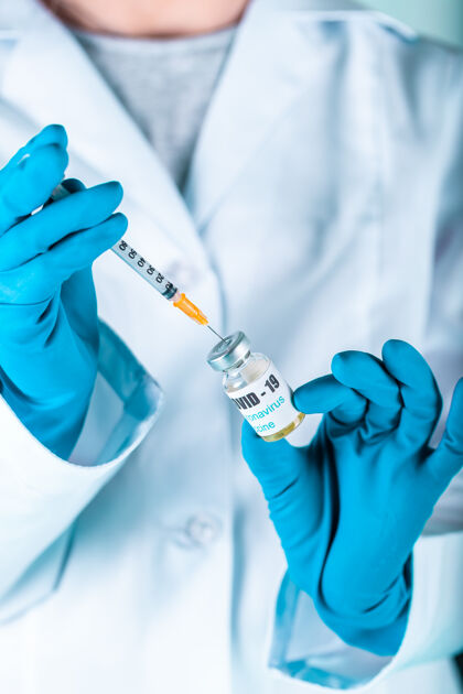 药物女医生或护士穿着制服 戴着手套 戴着口罩 在实验室里拿着带有冠状病毒疫苗标签的药瓶疫苗瓶医疗手套科学