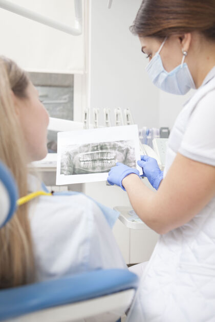 牙痛一个牙医和她的病人看牙科x光扫描的垂直后视图照片医学健康口腔科