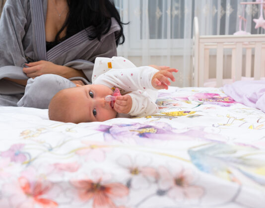 室内早上 一个可爱的婴儿和妈妈在床上嬉戏分娩可爱母性