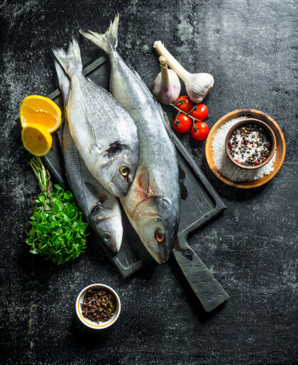 食物把新鲜的鱼放在砧板上 放上香草 香料 西红柿和大蒜生的烹饪配料