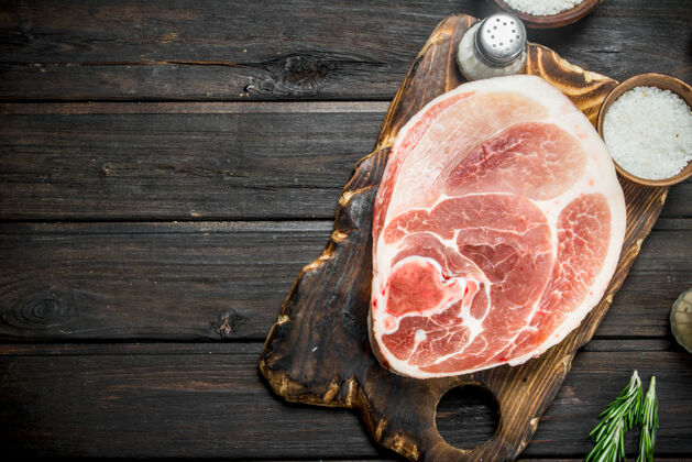 蛋白质生肉排配迷迭香董事会木制背景部分胡椒肉