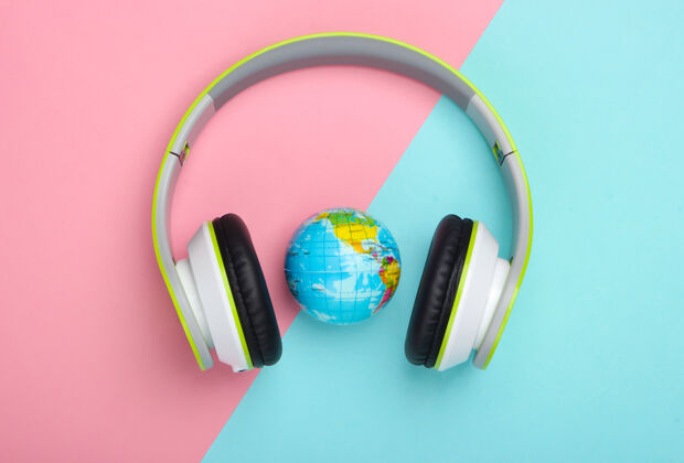 声音立体声耳机和地球仪在蓝色和粉色的表面顶视图艺术连接