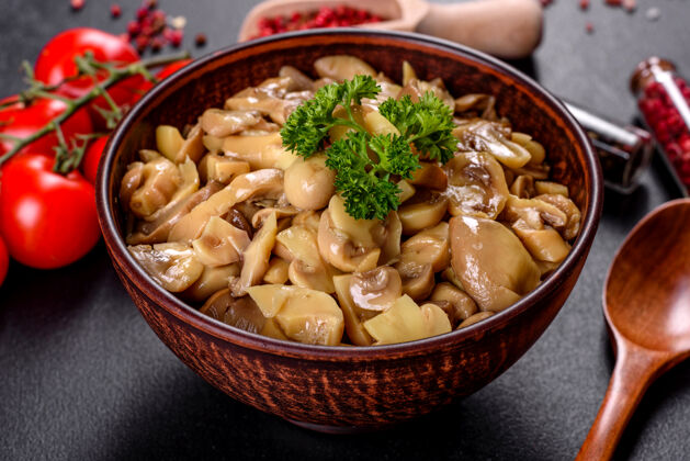 健康新鲜美味的辛辣蘑菇罐头与香料和草药在陶瓷菜肴在黑暗的混凝土背景木耳菜开胃菜