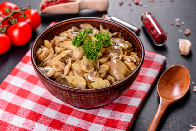 蔬菜新鲜美味的辛辣蘑菇罐头与香料和草药在陶瓷菜肴在黑暗的混凝土背景碗罐头开胃菜