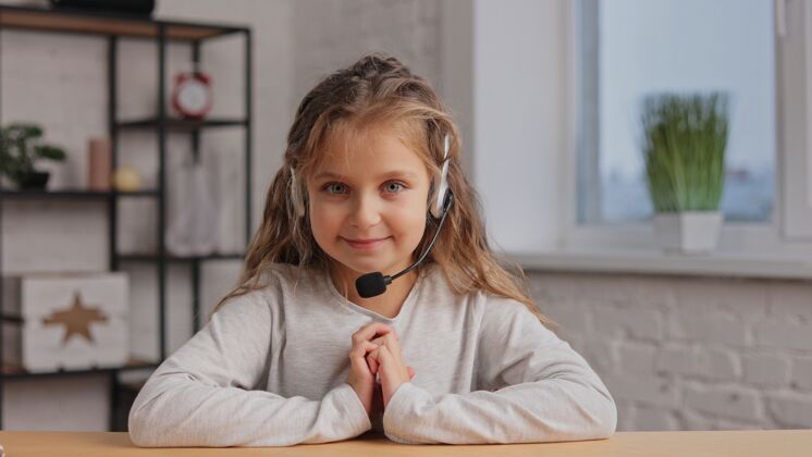 老师快乐可爱的小女孩戴着耳机微笑着上网摄像机.录音虚拟博客 在线视频会议 视频通话谈话解释讲座