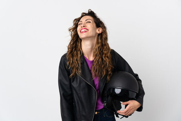 人年轻的白人妇女拿着摩托车头盔大笑墙夹克黑发
