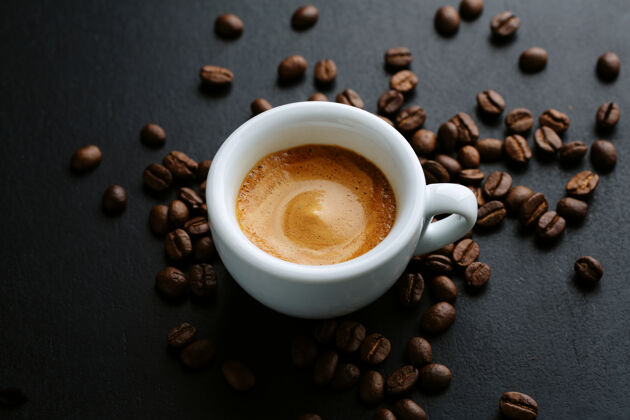 简单美味的浓缩咖啡 放在杯子里 周围放着咖啡豆勺子特写深色背景商店顶部特写