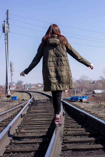 年轻那个女孩走在前面的铁路上路路冒险