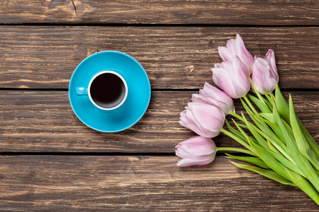 杯子一杯咖啡和一束郁金香放在木头表面咖啡温暖饮料