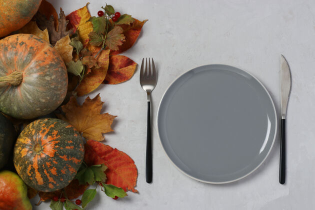 中心感恩节的餐桌上装饰着南瓜和灰色表面上的彩色叶子秋天背景静物光明