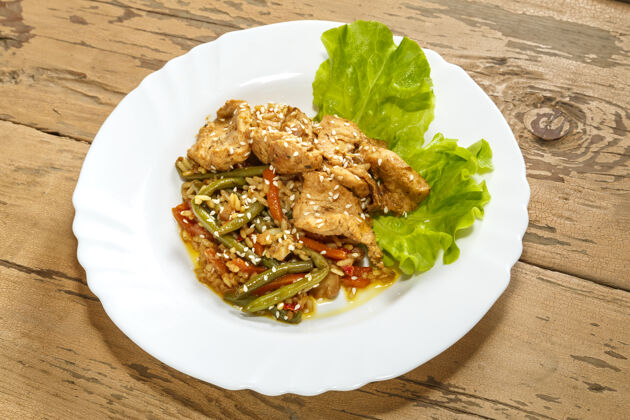 切片蔬菜 米饭 鸡肉 芝麻 沙拉叶 放在木桌上的盘子里酱油芝麻泰国菜