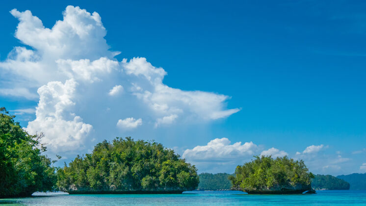 岛屿巴图利马附近的绿岩 甘岛上的生物多样性度假村 背景是多贝莱生态度假村 乌莱岛 西巴布亚 拉贾安帕特 印度尼西亚礁石投标旅游