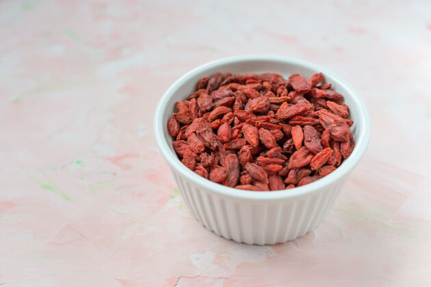 成分干枸杞在一个瓷碗上呈粉红色 健康吃素食和超级食品的概念回春有机植物