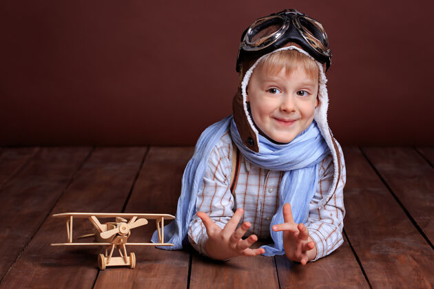 水平一个戴着飞行员头盔 戴着蓝色围巾 坐着木飞机的帅哥的画像航空孩子飞机