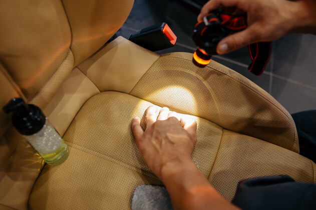 洗涤剂工人用手电筒检查汽车座椅的污垢 干洗和细节擦亮车辆车