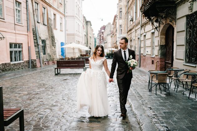 城市一对相爱的新婚夫妇走在巴黎的街道上lviv.新婚夫妇是散步婚礼走建筑浪漫两个