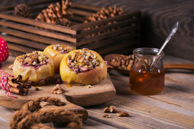 菜肴在木制砧板上塞满浆果 核桃和蜂蜜的烤苹果厨房木头肉桂