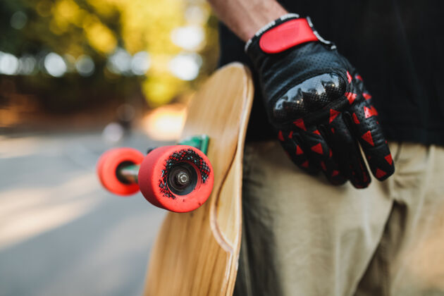 道路那家伙拿着一块红色的木板轮子滑板在永恒中城市高中高质量的照片年轻人人滑板