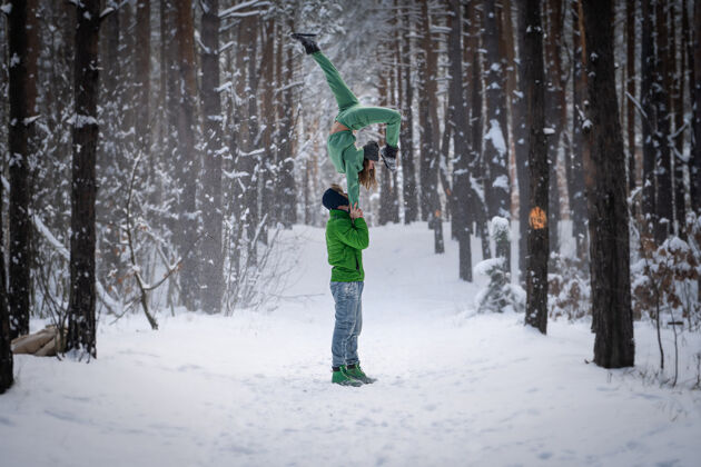 牵手杂技二重唱在冬季的雪林中摆出漂亮的姿势体操支持灵活