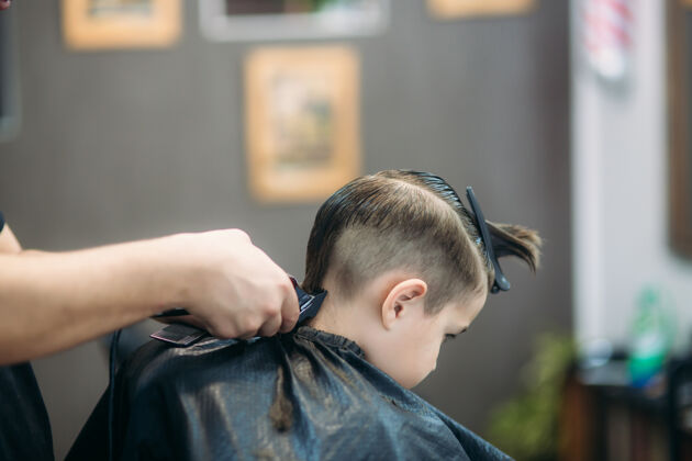 发型师小男孩坐在理发店的椅子上被理发师理发理发剃刀男孩