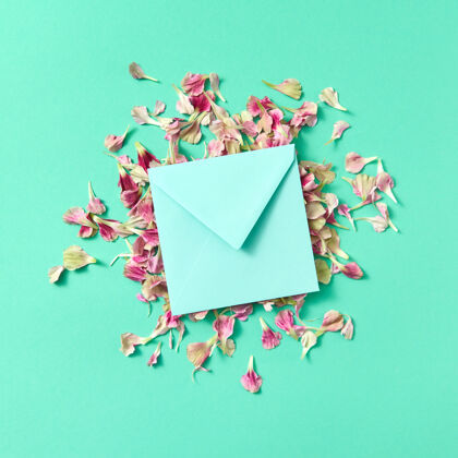 空白在绿松石色背景上的花瓣上用手工制作的信封和作的贺卡空间.平面躺着嘲笑-起来颜色妈妈信息