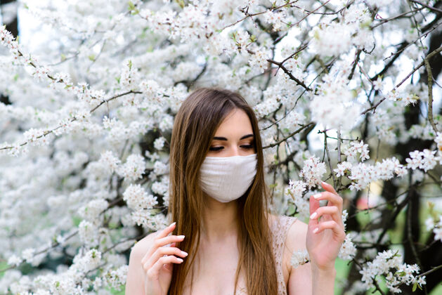 花园在春天的花园里 一个戴着无菌医用防护口罩的年轻女子空气流行病冠状病毒