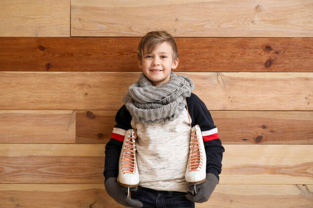 冰可爱的小男孩用冰鞋抵着木头衣服鞋子温暖