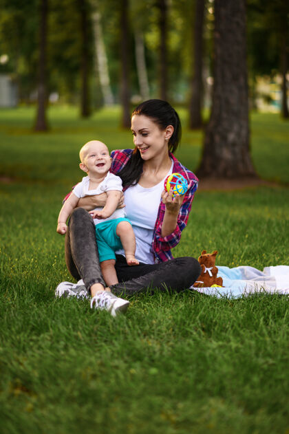 妈妈妈妈和她的小宝宝在夏日公园的草地上摆姿势父母女性孩子